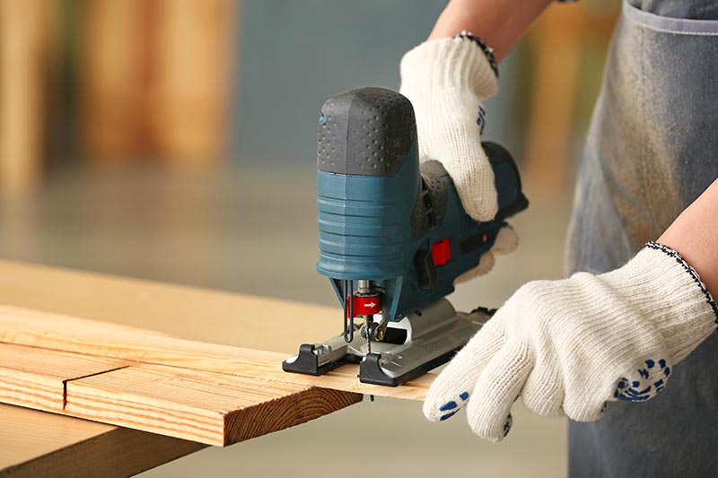 carpenter cutting timber with jigsaw